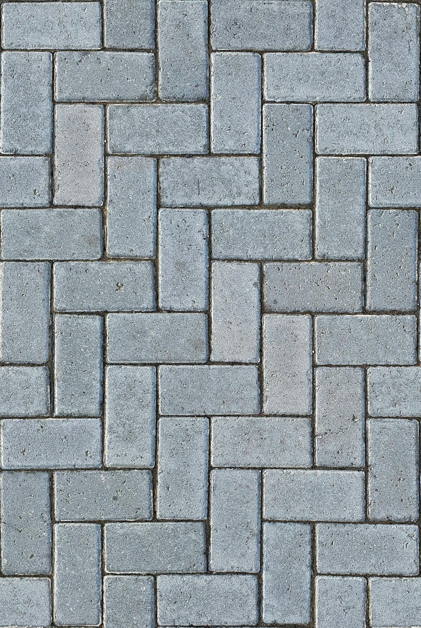 Detailed gray textured pavement with a classic herringbone pattern, ideal for design backgrounds.